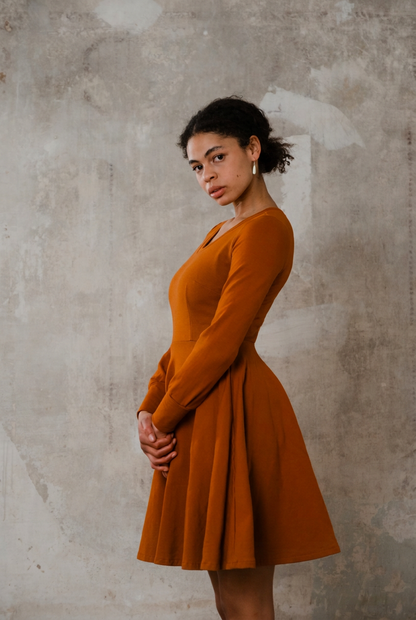 Sweatkleid Cinnamon in Rostrot von der Seite mit langen Ärmeln, tailliertem Schnitt und weit abstehendem Tellerrock